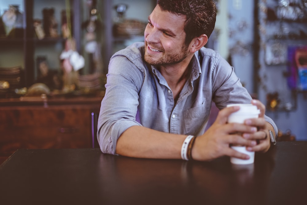 man holding cup on table