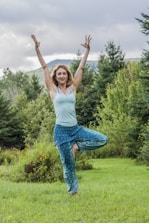 A person practicing yoga outdoors surrounded by trees and earthy colors.