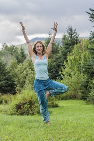Anil Kumar Jha demonstrating a gentle yoga pose outdoors surrounded by greenery.