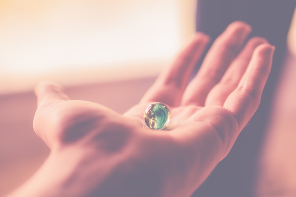 persons hand holding blue and clear marble toy