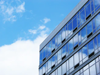 A sleek modern UK university building with glass facades reflecting a clear blue sky.