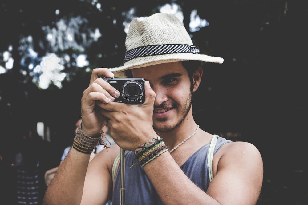 selective focus photo of man holding black compact camera