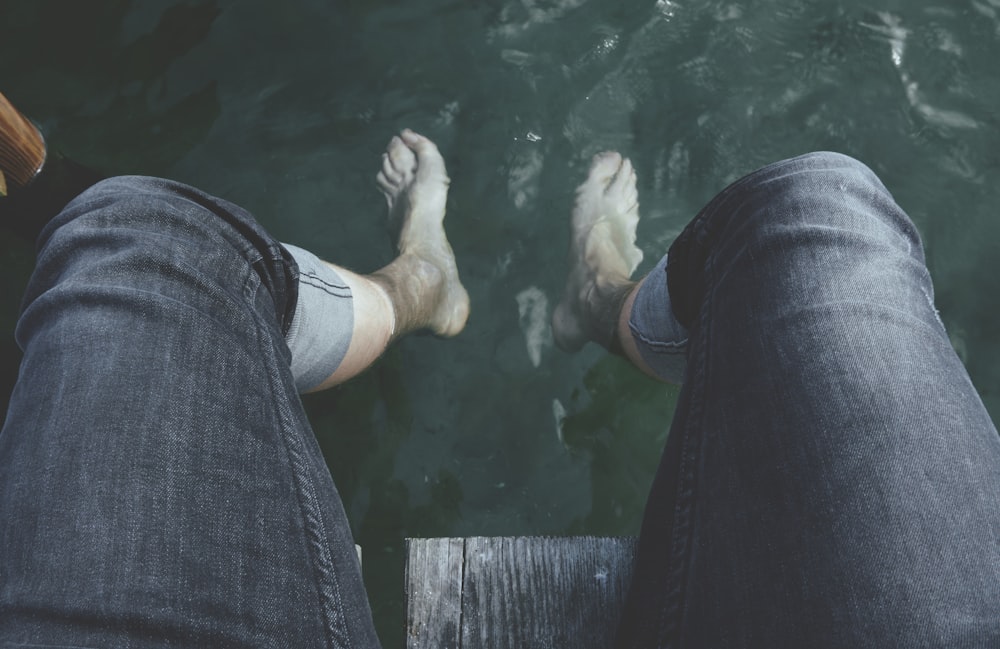 persona con los pies colgando sobre el agua