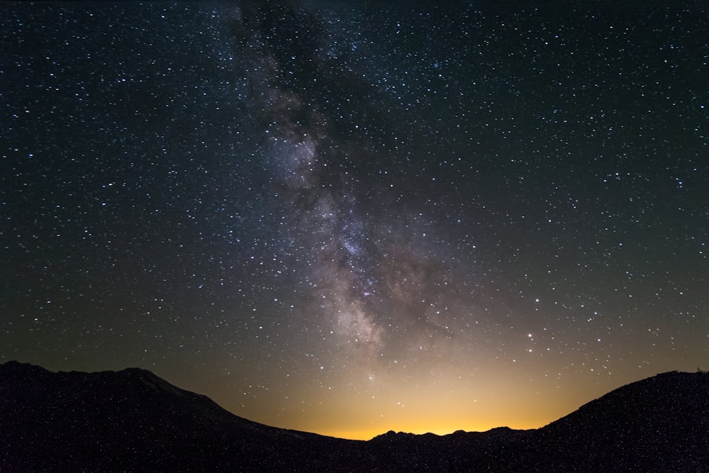 silhouette of mountain under starry night