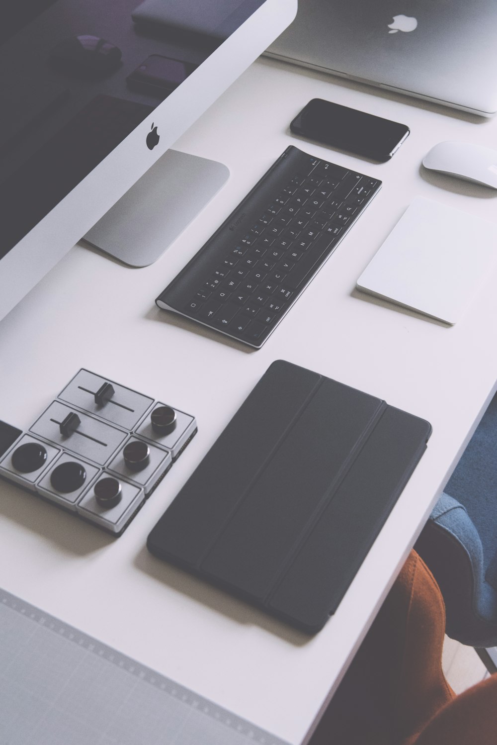 黒いiPadケース、Appleワイヤレスキーボード、白いテーブルの上のiMacのフラットレイ写真