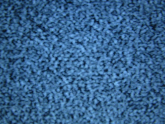 A close-up of blue static noise pattern resembling what might be seen on an old television screen without a signal. The image is uniformly filled with small light and dark blue speckles creating an abstract, textured appearance.