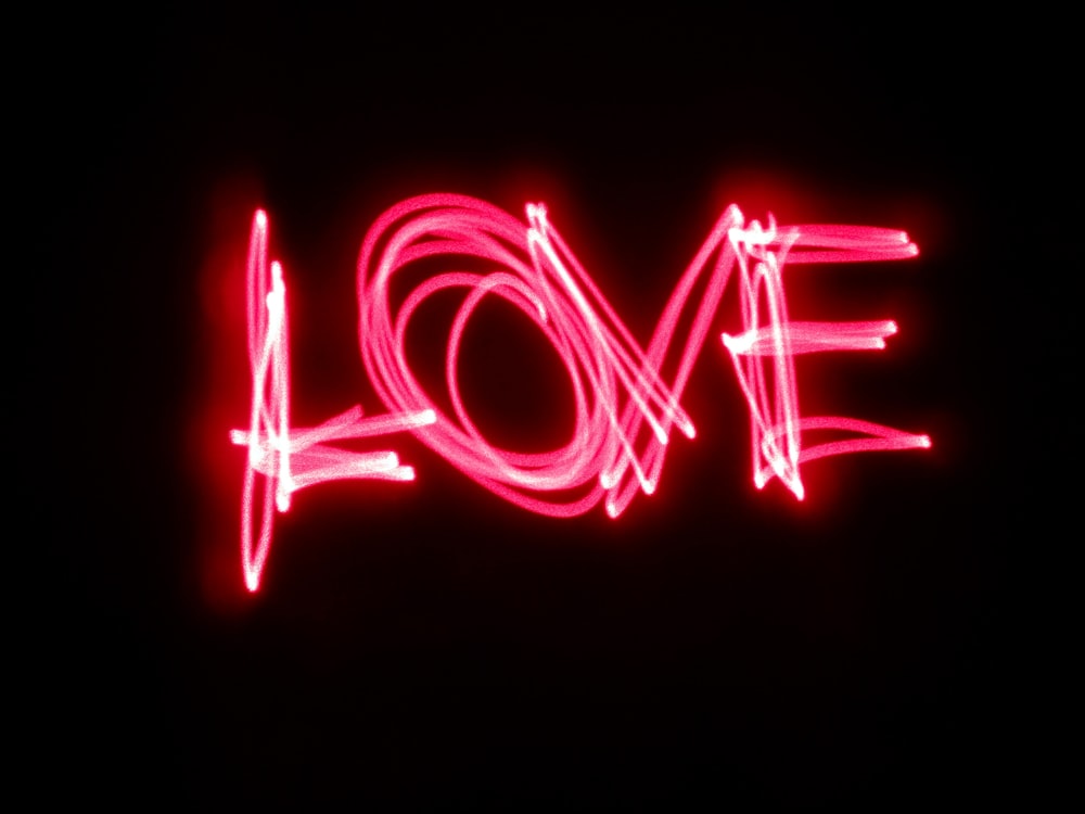 A pink neon light painting that says "Love."