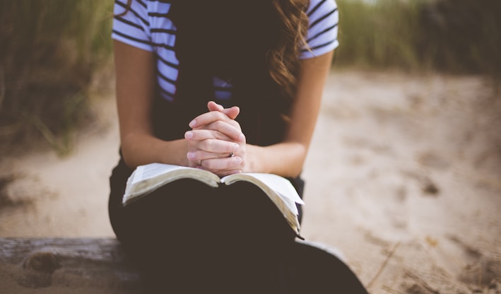 woman sitting on brown bench while reading book