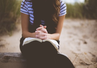 woman sitting on brown bench while reading book