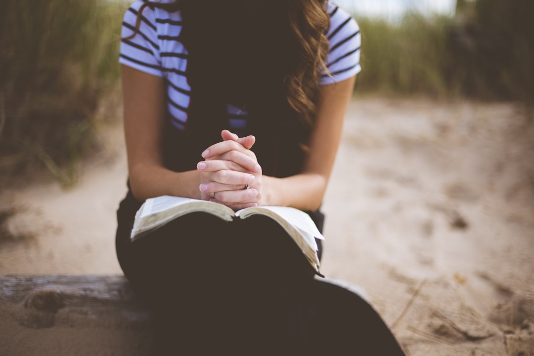 woman sitting on brown bench while reading book,