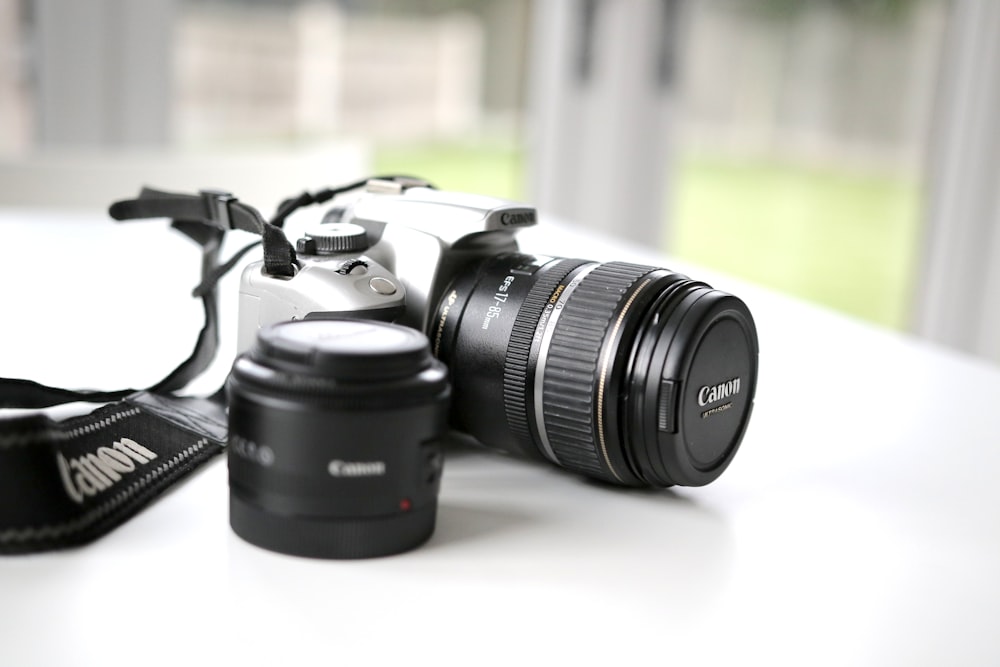 흰색 표면에 검은색 Canon DSLR 카메라