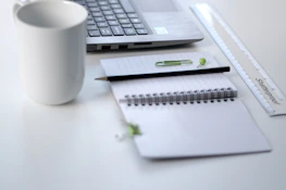 Bright and clean workspace showing a laptop and open notebook filled with business plans.
