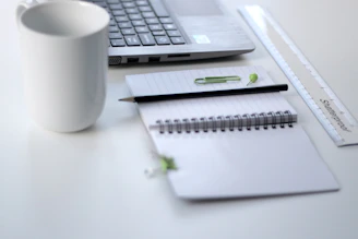 A clean workspace featuring a sleek laptop open to a digital productivity guide, with a notebook and pen nearby.