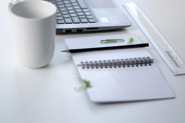 A clean, modern workspace with a laptop, notebook, and a cup of coffee, reflecting a calm and organized bookkeeping environment.