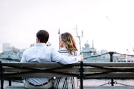 couple sitting on bench near body of water