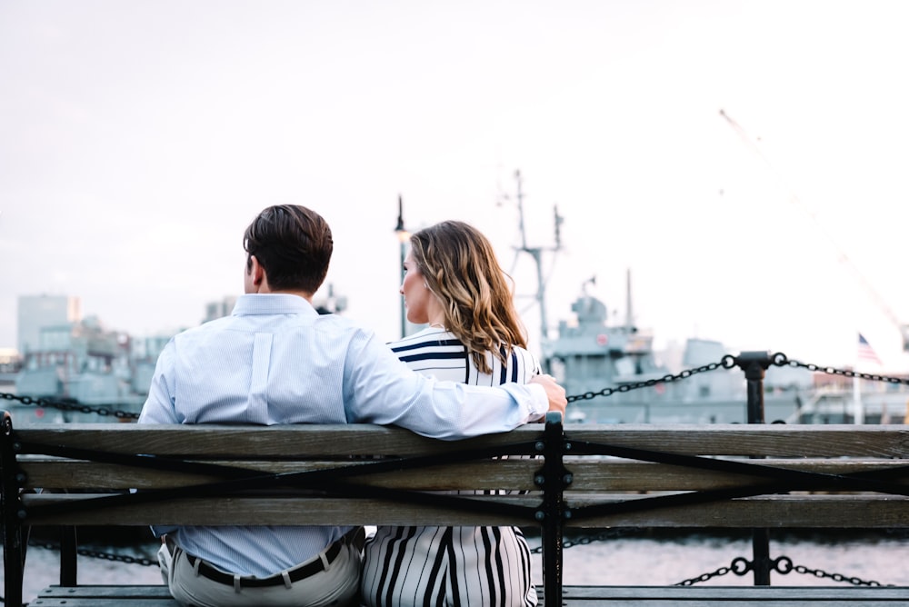 couple sitting on bench near body of water