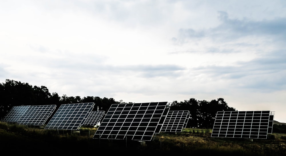 silhouette photography of assorted solar panel behind trees