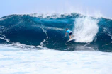 A surfer riding a towering wave under a stormy sky, water spraying everywhere.