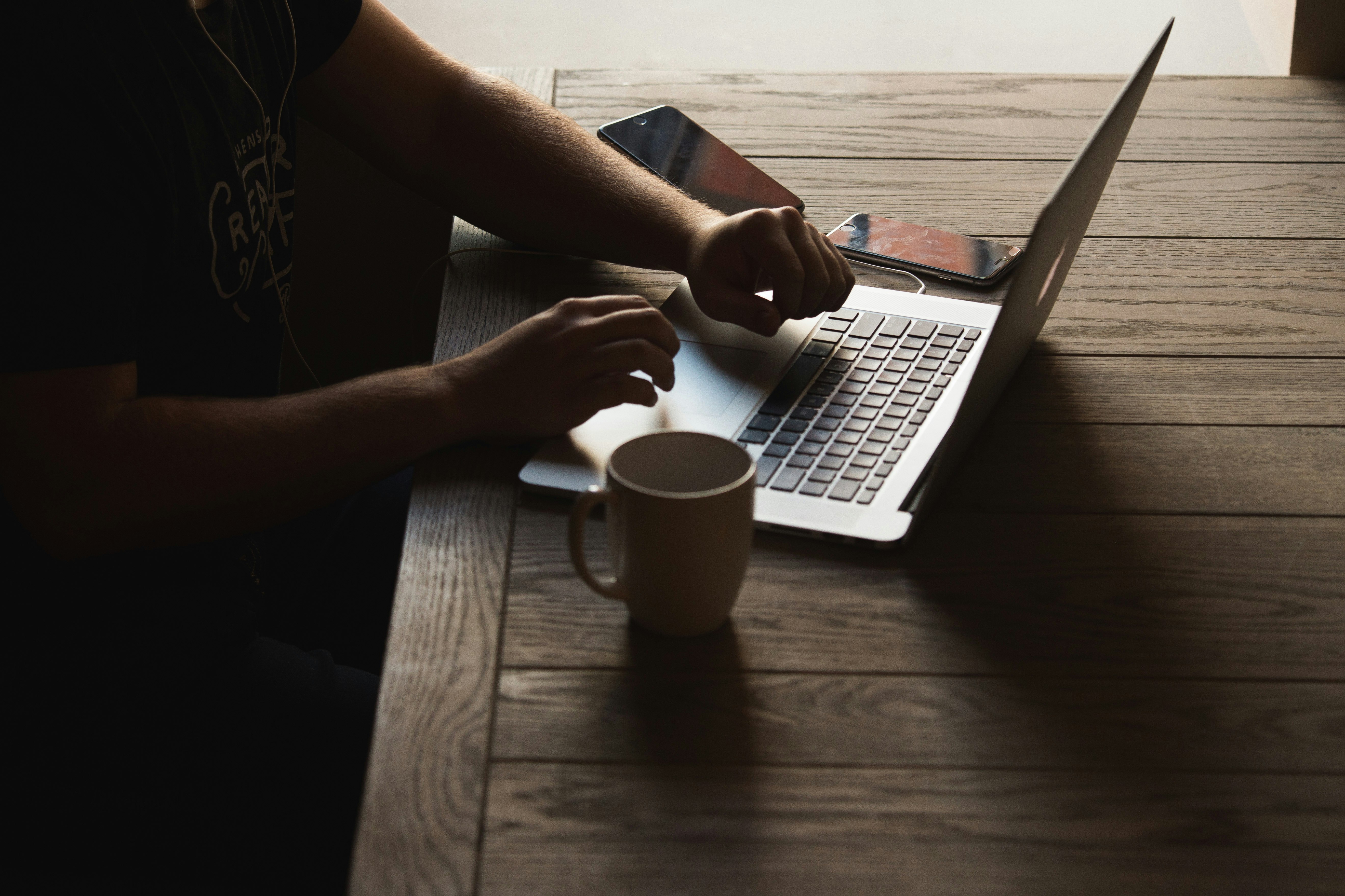 gray laptop computer on brown wooden table beside person sitting on chair