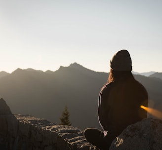 person wearing knit cap facing mountain