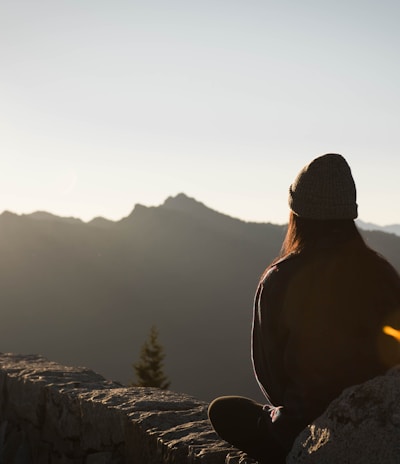 person wearing knit cap facing mountain