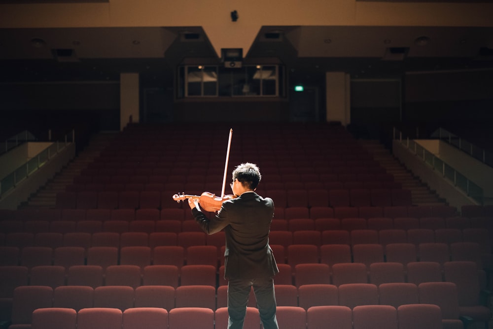 homme debout devant la scène jouant du violon