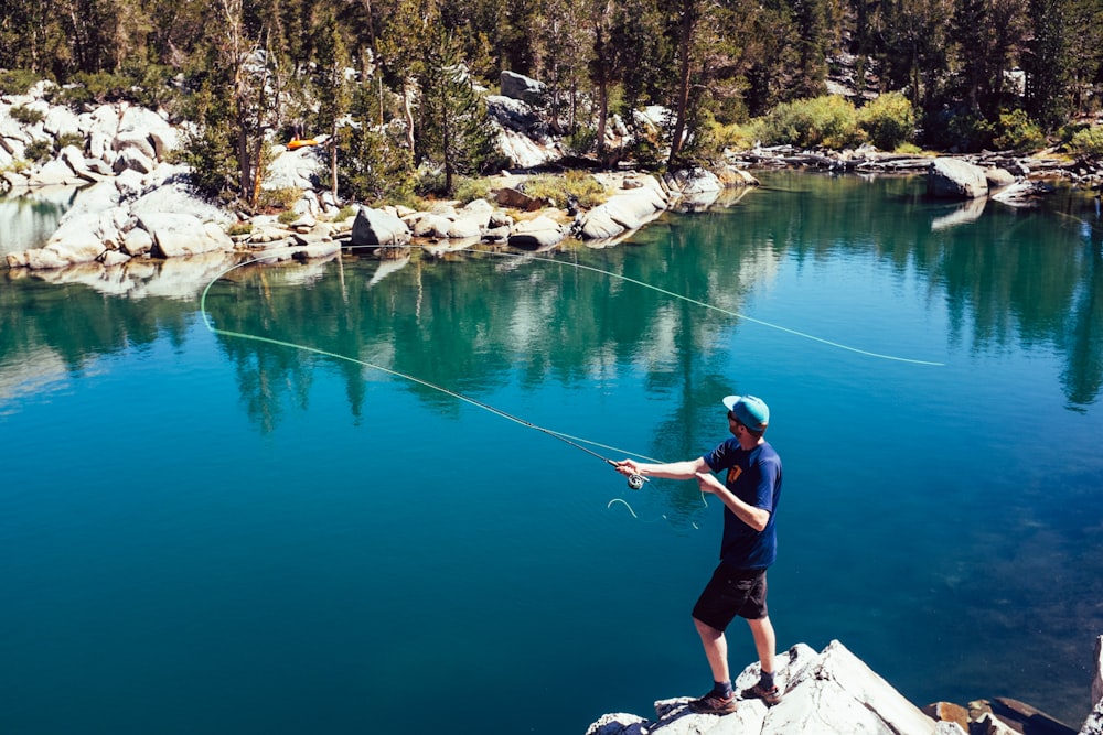 a man standing on top of a rock next to a lake