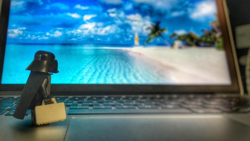 A Lego Darth Vader toy staring at a laptop screen while standing on the keyboard.