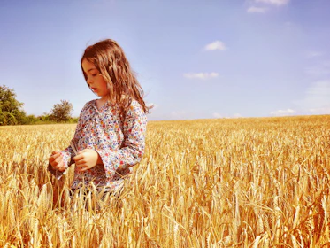 A cinematic scene of a young girl standing confidently in a golden field under a sparkling sky.