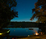 Serene lakeside campsite under a star-filled night sky.