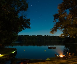 A peaceful lakeside campsite under a starry night sky.