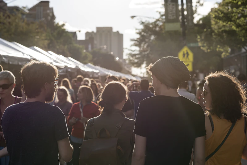 Crowd walking past vendor tents at a summer street fair