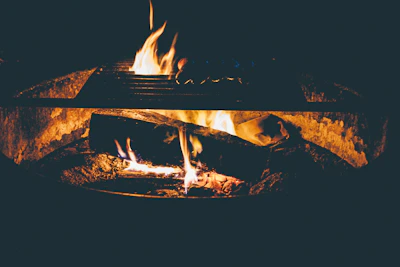A cozy campfire glowing warmly as a family shares stories under a starry night sky.