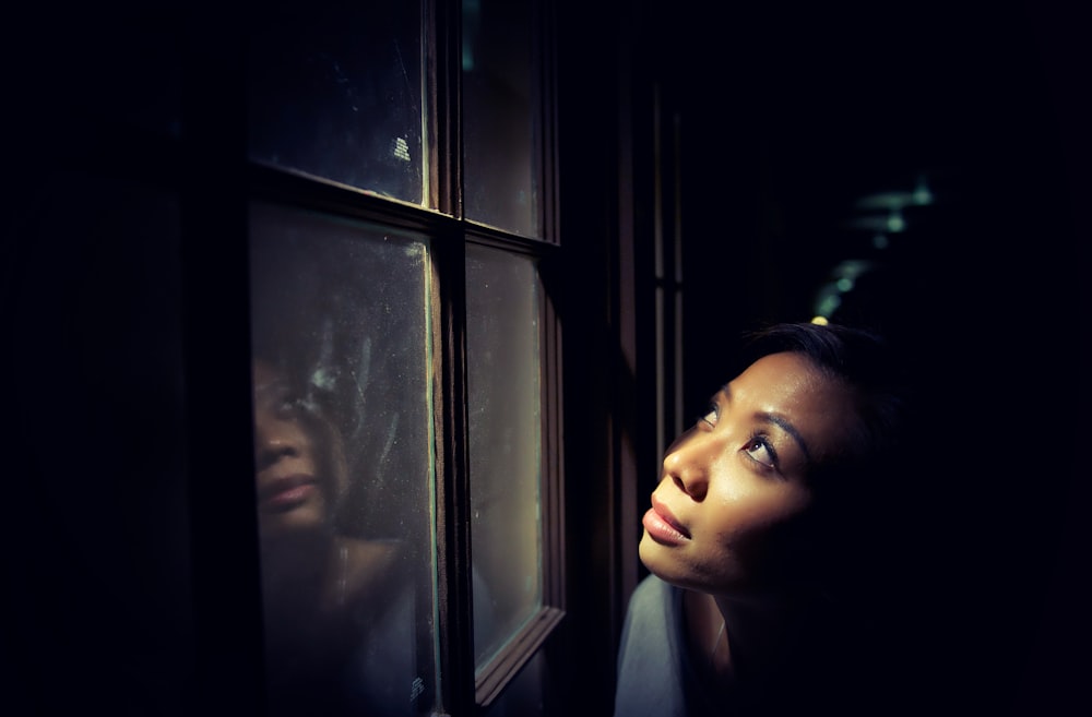 Frau schaut hinter dem Fenster nach oben