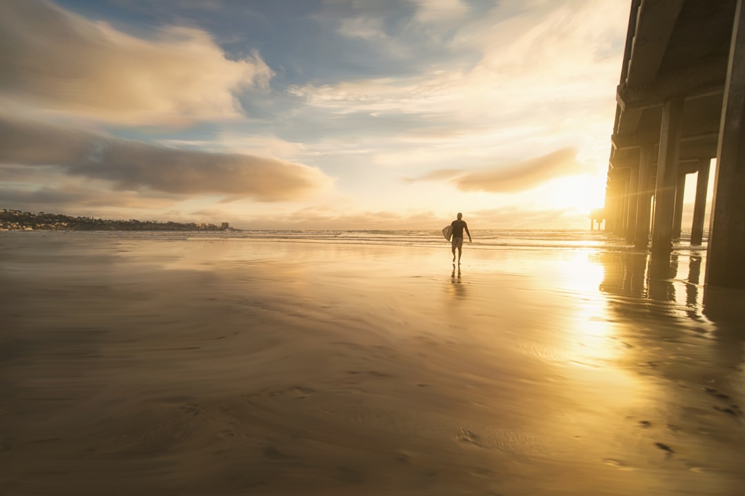 person walking under bridge, san diego surfer sunset