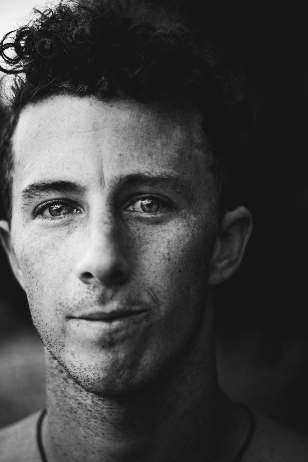 Photo en niveaux de gris d’un homme souriant regardant la caméra