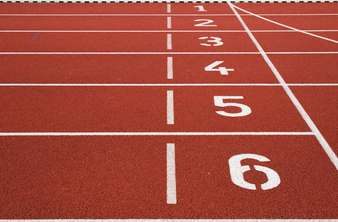 Numbered lanes at the starting line of a red running track