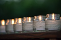 An elegant row of minimalist soy candles in glass jars, lit and casting warm light.
