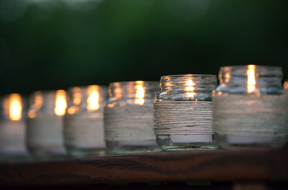 a row of lit candles sitting on top of a wooden table