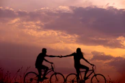 woman on bike reaching for man's hand behind her also on bike