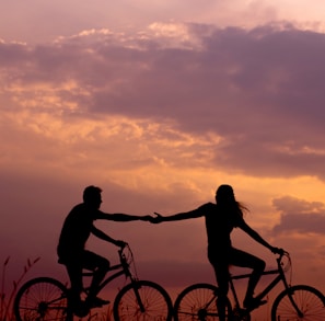 woman on bike reaching for man's hand behind her also on bike