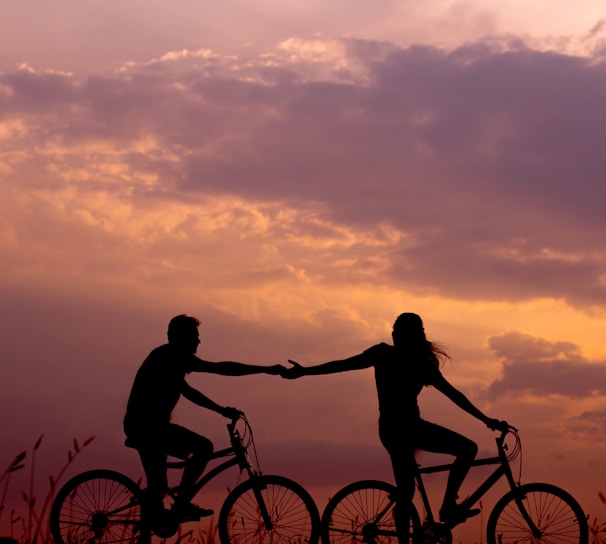 woman on bike reaching for man's hand behind her also on bike