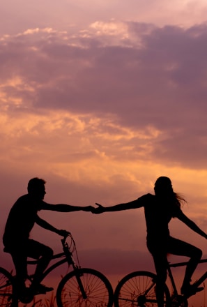 woman on bike reaching for man's hand behind her also on bike