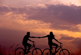 woman on bike reaching for man's hand behind her also on bike