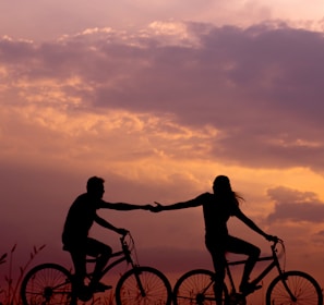 woman on bike reaching for man's hand behind her also on bike