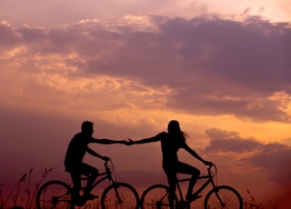 woman on bike reaching for man's hand behind her also on bike