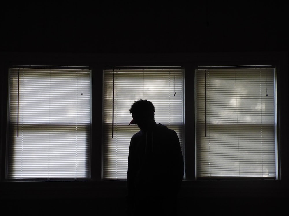 Homme debout devant les stores des fenêtres