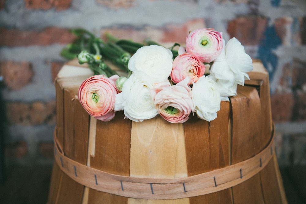 茶色の木製のバケツに白とピンクのバラ