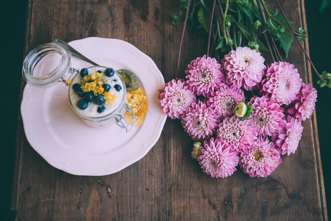 pink dahlia flowers beside ceramic plate with jar