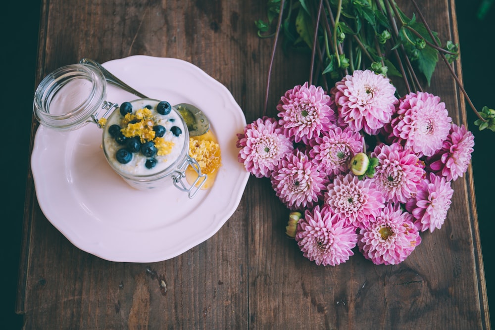 pink dahlia flowers beside ceramic plate with jar